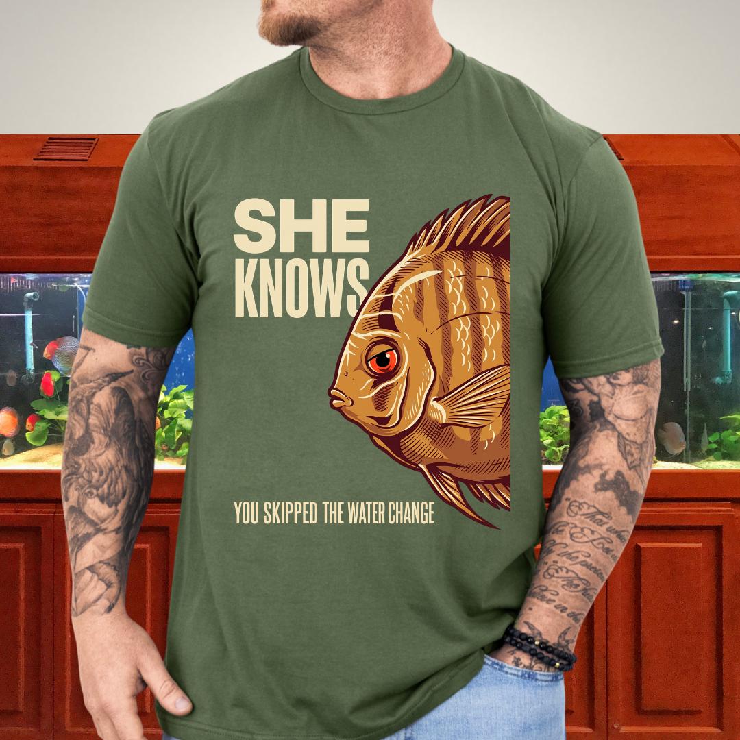 Illustrated wild-type discus with She Knows You Skipped The Water Change text on a military green unisex t-shirt