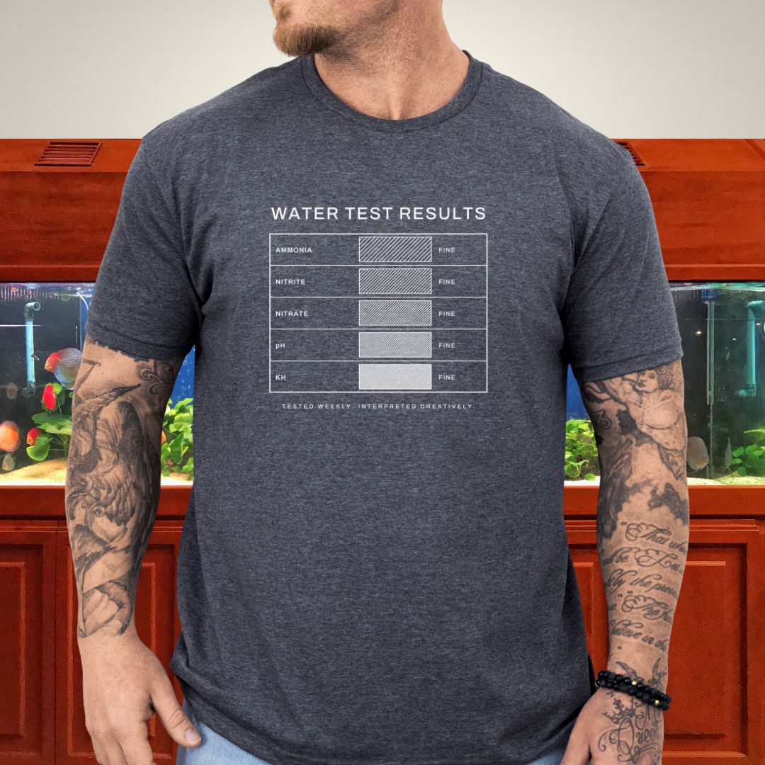 Line-art water test comparison card design (ammonia, nitrite, nitrate, pH, KH) on a military green unisex t-shirt