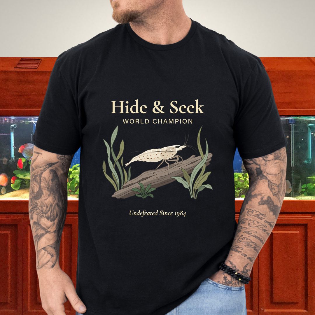 Editorial illustration of an Amano shrimp on driftwood with Hide and Seek World Champion text on a black unisex t-shirt